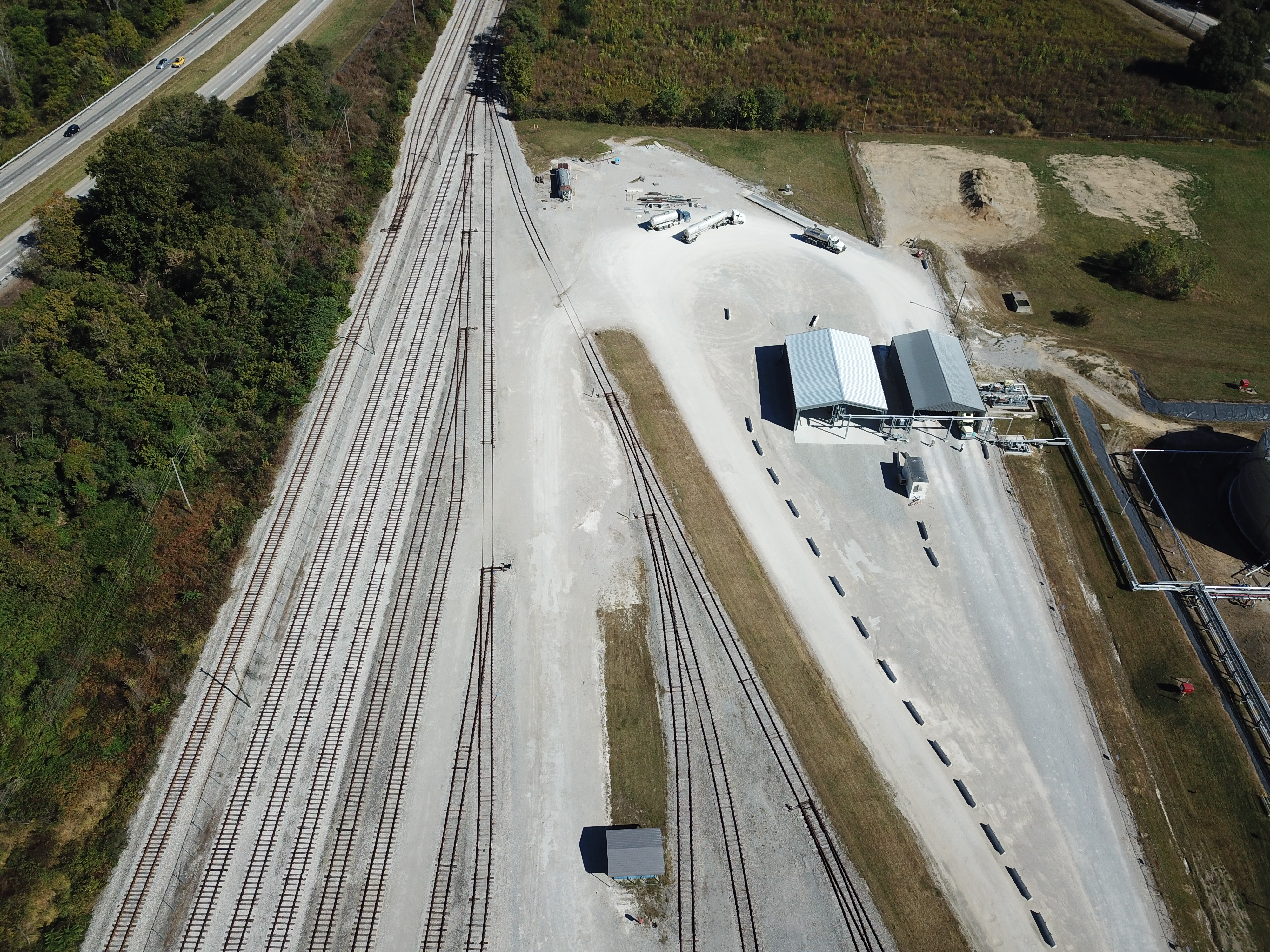 Aerial view of the Arrow Belpre HCL rail terminal — multi-track rail yard, highway, terminal buildings, and tree-line
